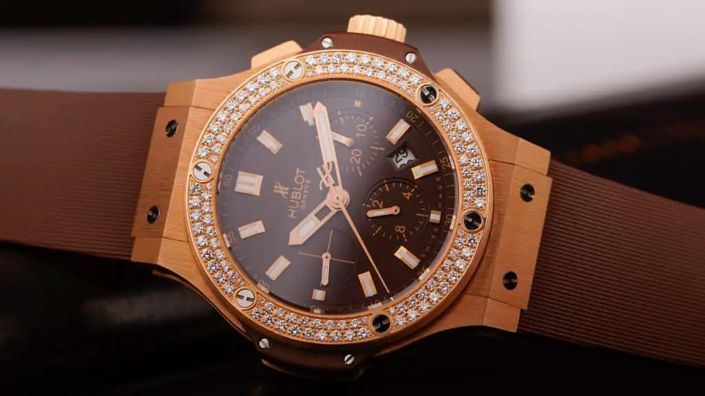 A classy Hublot watch with a dark brown dial, golden case, and diamonds atop the bezel.